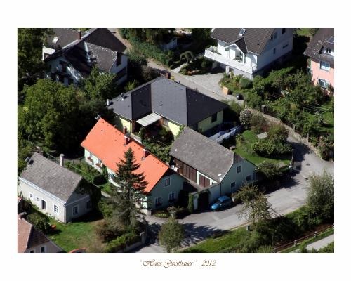 Aerial view of a residential area with several houses, including a house with a red roof.