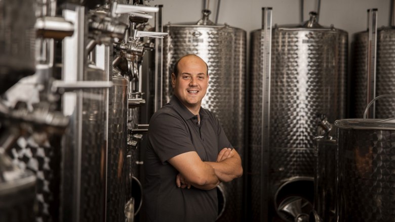 Man in a wine cellar with stainless steel barrels.
