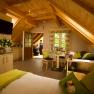 Cozy vacation apartment with wooden furnishings, sloping ceilings and green accents. Two people can be seen on a balcony in the background.
