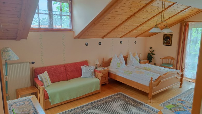 Zimmer mit Dachschräge, Doppelbett und Couch