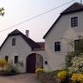 A white country house with a brown roof and garden.