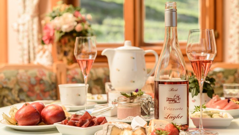 Fr&uuml;hst&uuml;ckstisch mit Obst und K&auml;se und einer Flasche Frizzante