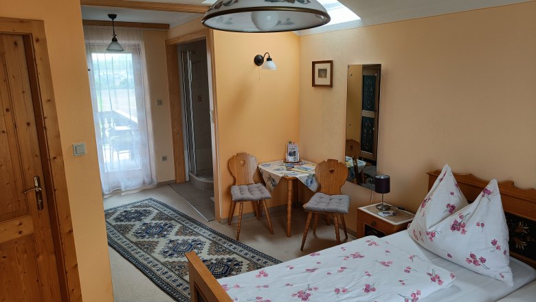 Zimmer mit Bett, Tisch und 2 Stühlen