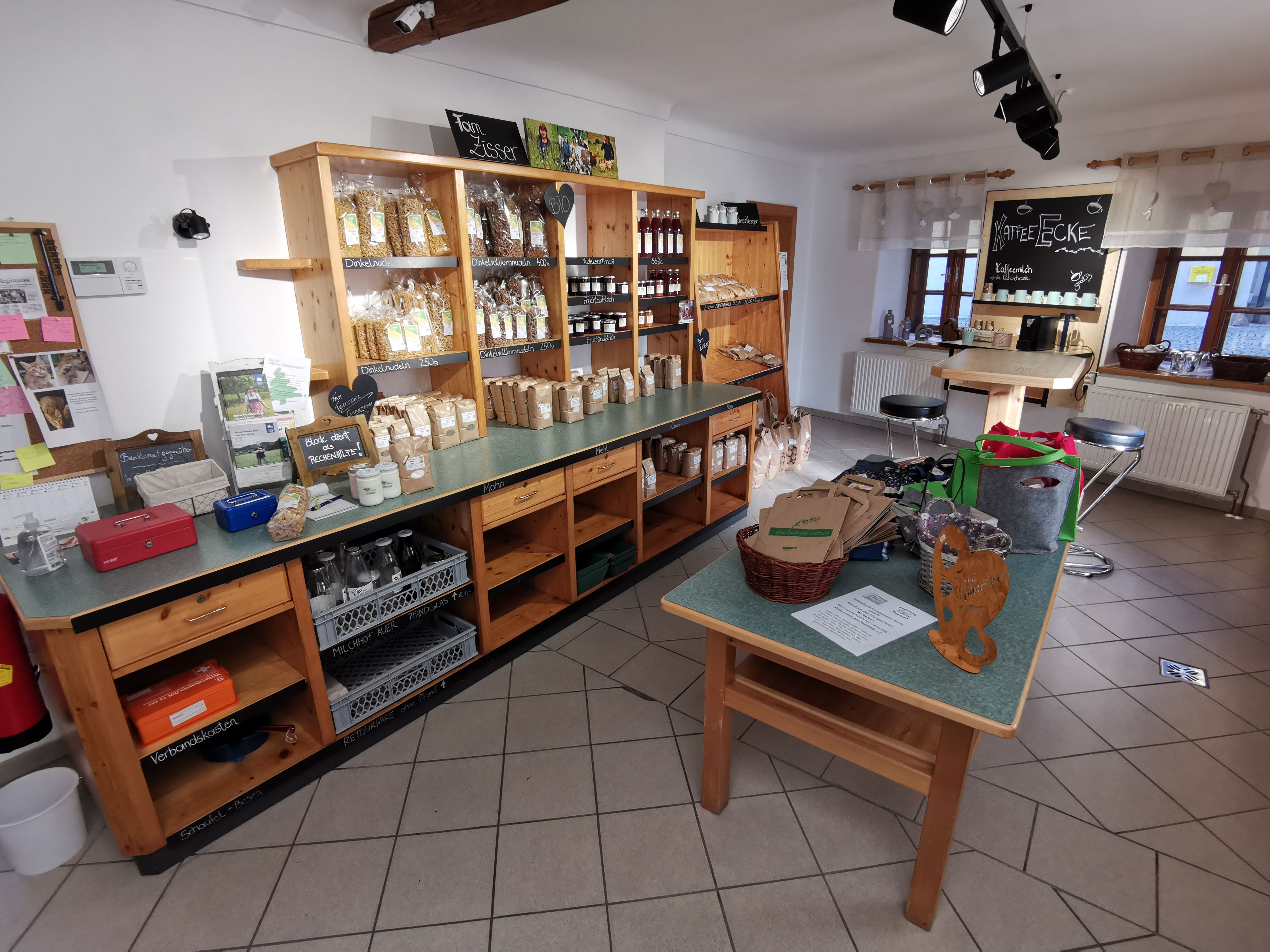 Innenraum des Hofladens mit einem Tisch und Kästen mit Produkten