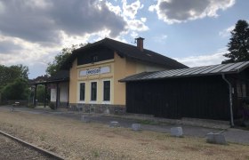 Emmersdorf station with yellow building and tracks in the foreground.