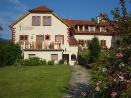 Ein großes, traditionelles Haus mit rotem Dach und blühendem Garten im Vordergrund.