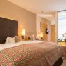 Modern hotel room with double bed, stylish lamps and large window with landscape view.