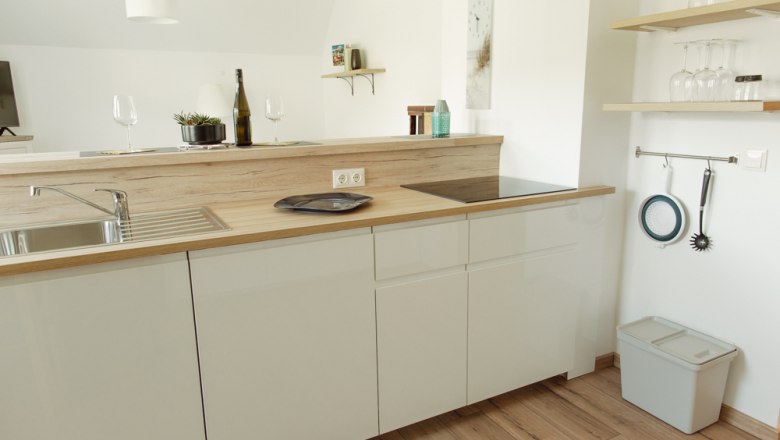 Modern kitchen with wooden worktop, sink, stove and shelves with glasses.