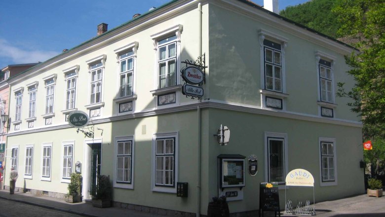 Historic building with green façade and several windows, signposted as an inn.