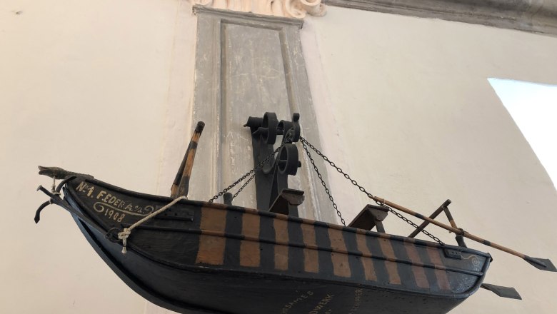 Modell eines historischen Ruderbootes an der Wand eines Museums ausgestellt.