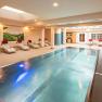 Ein moderner Indoorpool im Hotel-Spa mit Liegestühlen und Wandmalereien