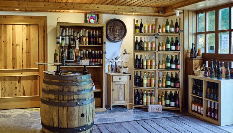 Innenansicht eines rustikalen Weinladens mit Holzregalen und Weinfässern.