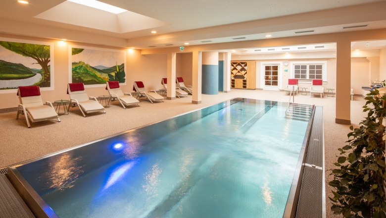 Ein moderner Indoorpool im Hotel-Spa mit Liegest&uuml;hlen und Wandmalereien