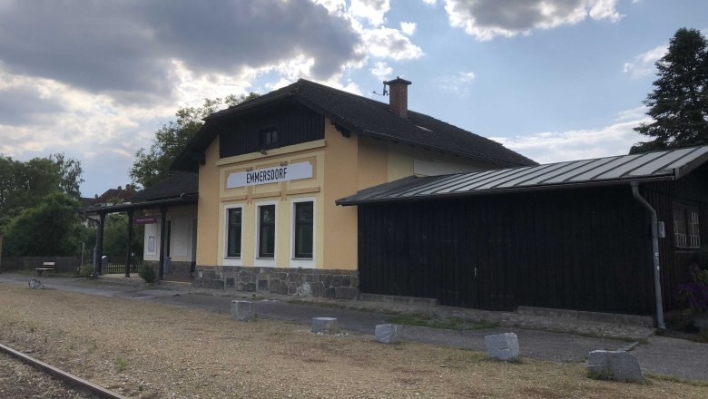 Emmersdorf station with yellow building and tracks in the foreground.