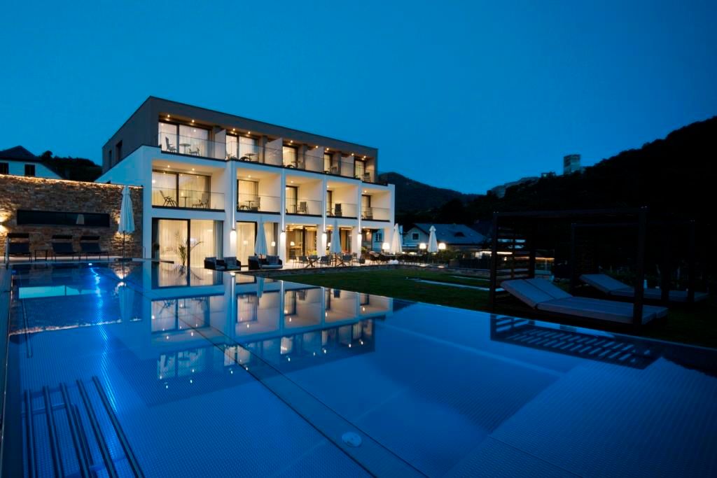 Modernes Boutique-Hotel mit beleuchtetem Pool bei Nacht.