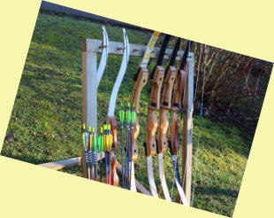 A stand with several bows and arrows on a meadow.