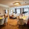 Elegant restaurant with laid tables, upholstered benches and hanging lamps at Luberegg Castle
