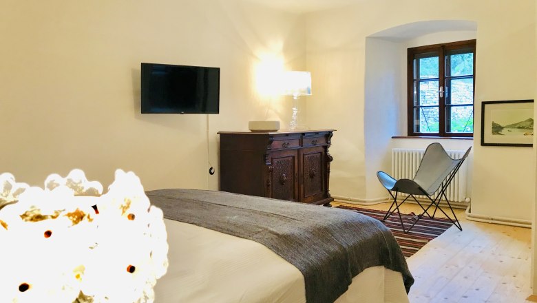 Schlafzimmer, © Fam. Georgoulopous Gemütliches Schlafzimmer mit Bett, antiker Kommode, Sessel und Wand-TV.