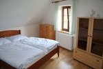 A bedroom with a double bed, wooden chest of drawers and wardrobe, light-colored walls and a window with a curtain.