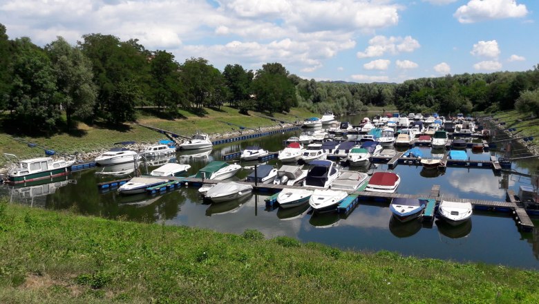 Boats in the Emmersdorf marina, surrounded by green trees and blue skies.