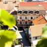 View of a building with the inscription 'Haus Oestreicher', surrounded by other houses and green leaves in the foreground.