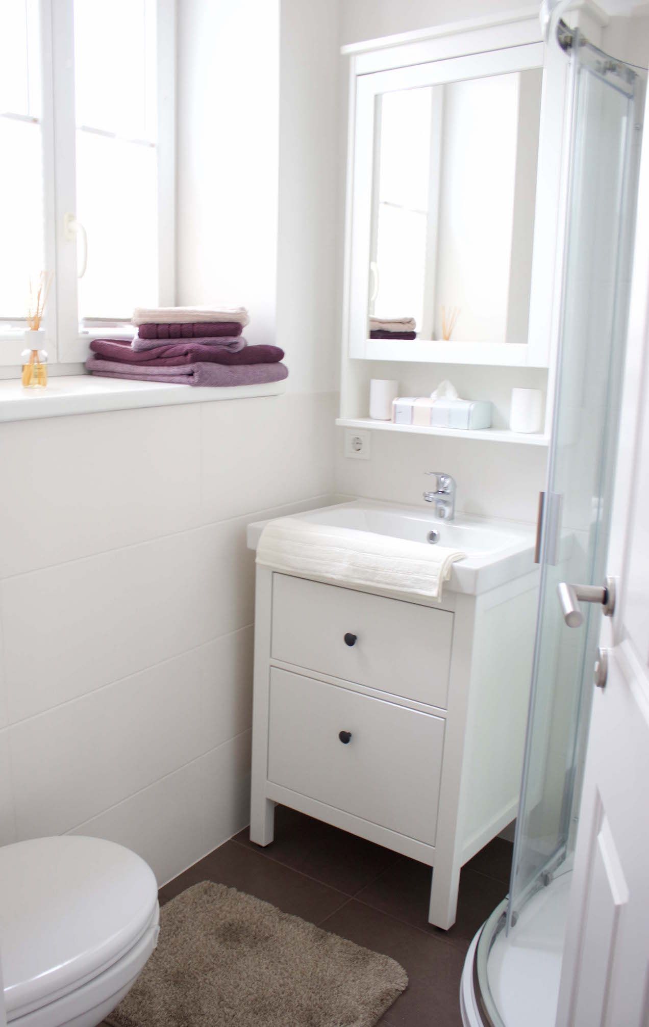 Modernes Badezimmer mit weißem Waschbecken, Spiegel, Handtüchern und Dusche.