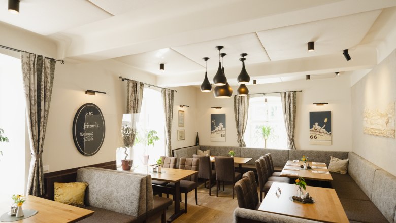 Modern restaurant with wooden tables, gray upholstered benches and stylish lamps.