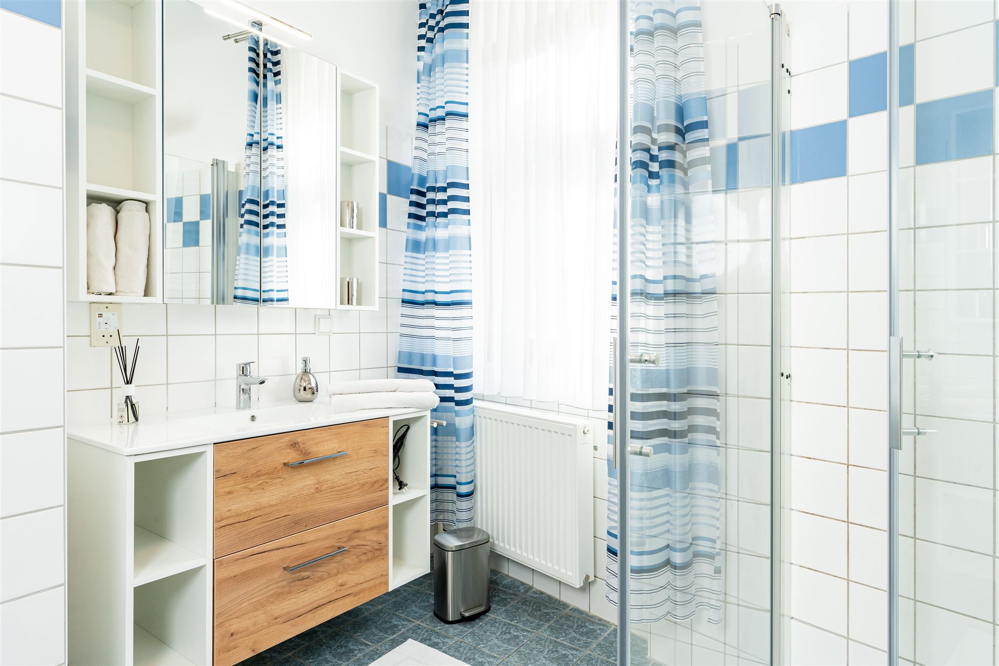 Modernes Badezimmer mit Holzschrank, Spiegel, Duschvorhang und Fliesen.