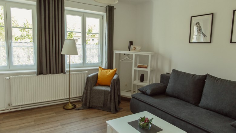 Bright living room with gray sofa, armchair, floor lamp and white furniture.
