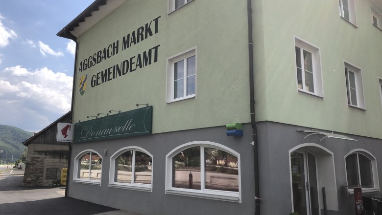 Grünes Gebäude des Gemeindeamts Aggsbach Markt mit Donauwelle-Schild.