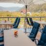 Terrace with tables, blue chairs and a view of the green landscape.
