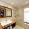 Modernes Badezimmer mit Holzdetails, Waschbecken, Spiegel und Glasdusche.