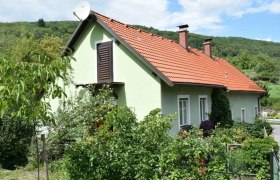 Green detached house from the outside with a red roof