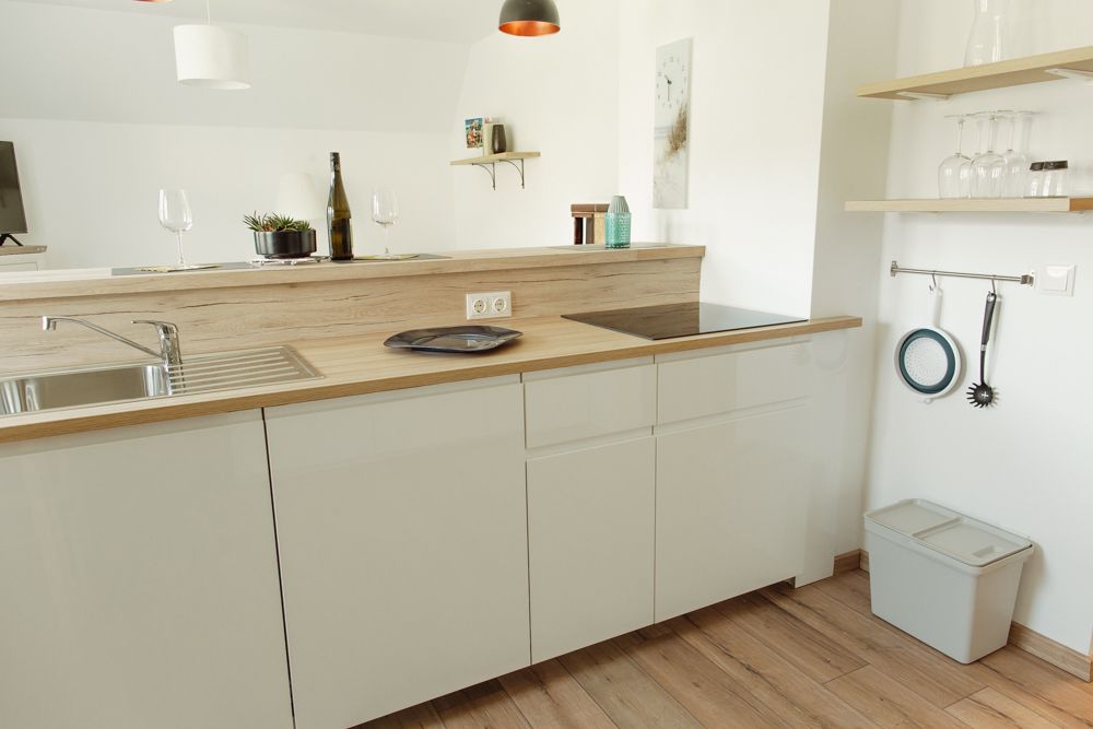 Moderne Küche mit Holzarbeitsplatte, Spüle, Herd und Regalen mit Gläsern.