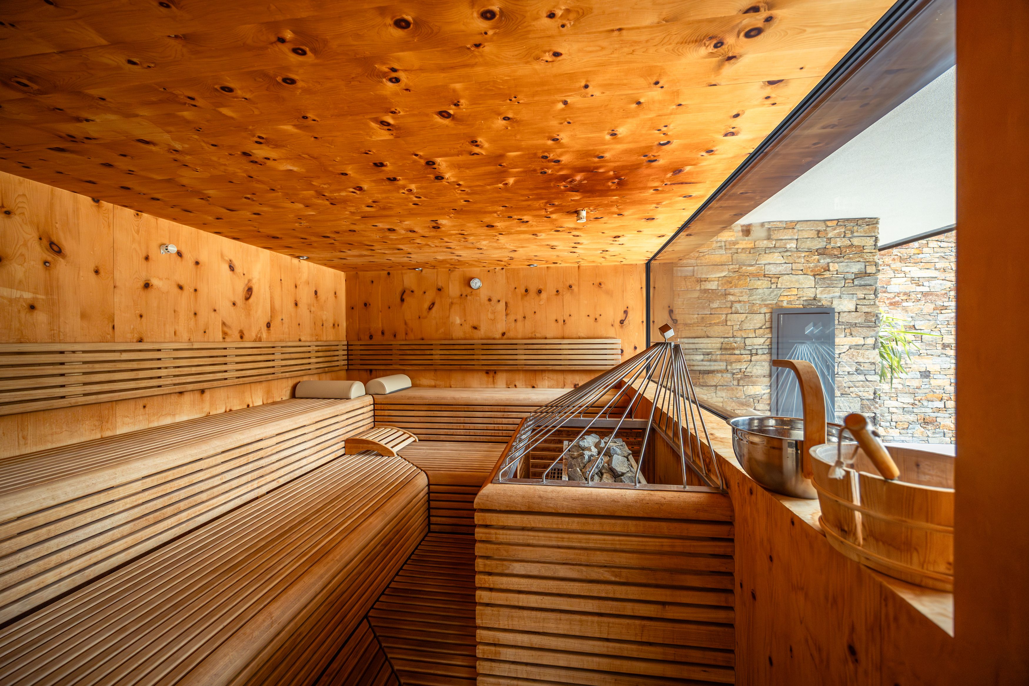 Innenansicht einer modernen Sauna mit Holzbänken und einem großen Fenster.